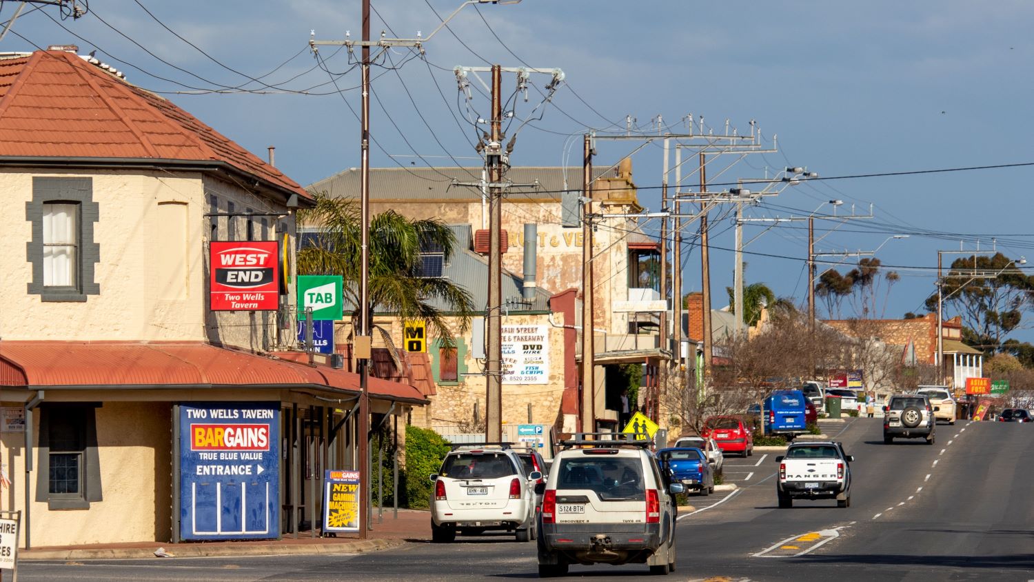 The Main Street of Two Wells stretching into the distance, with powerline cables filling the roadside.
