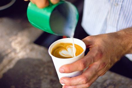 Close up photo of a hand pouring a barista coffee.